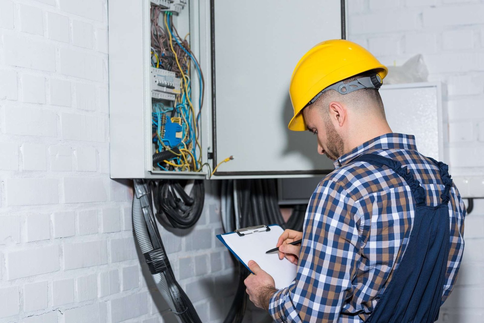 professional electrician inspecting wires in electrical box