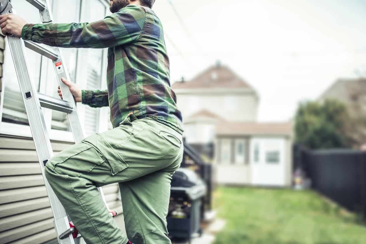 man performing home exterior repairs on a house