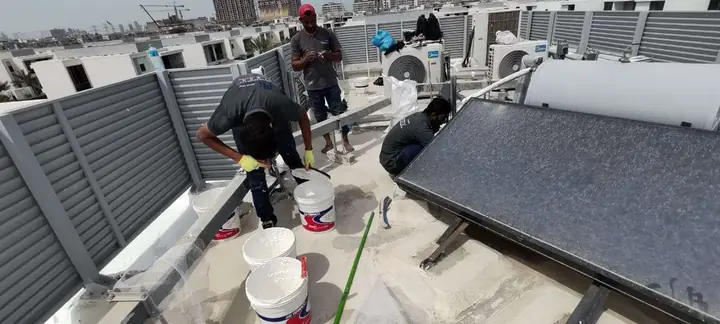 Crew applying reflective waterproof coating on a Dubai villa roof • #1 Waterproofing Company in Dubai & UAE Crew applying reflective waterproof coating on a Dubai villa roof