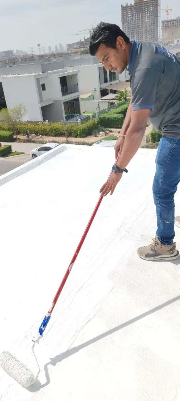 Technician rolling liquid waterproof coating onto a roof • #1 Waterproofing Company in Dubai & UAE • #1 Waterproofing Company in Dubai & UAE Technician rolling liquid waterproof coating onto a roof